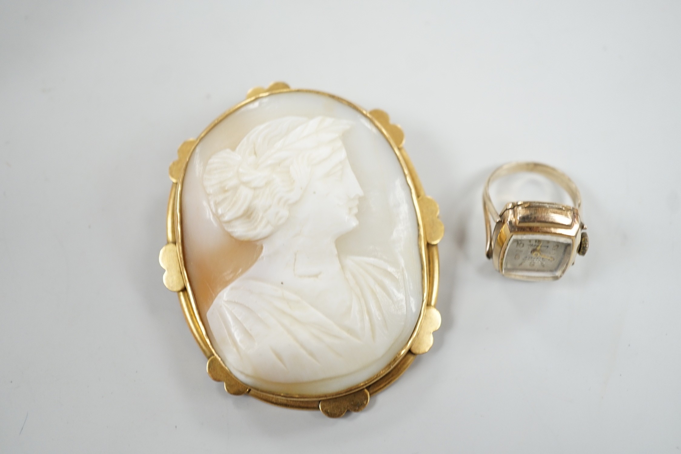 A pinchbeck mounted oval cameo shell brooch, 64mm and a gold plated watch ring.
